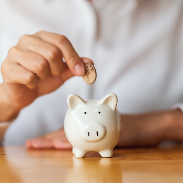 Person putting coins in a piggybank.