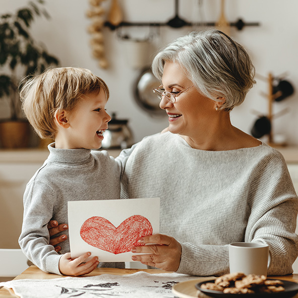 Grandmother and grandson smiling at eachother.