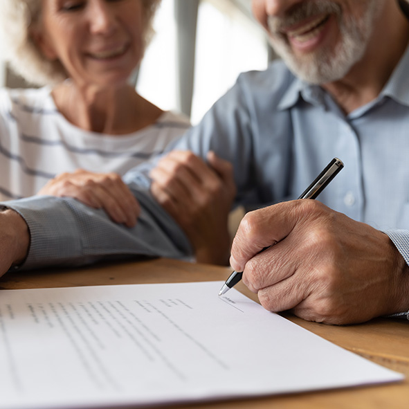 Elderly couple signing important document.