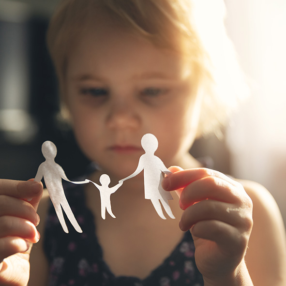 sad girl holding up paper cut out of family