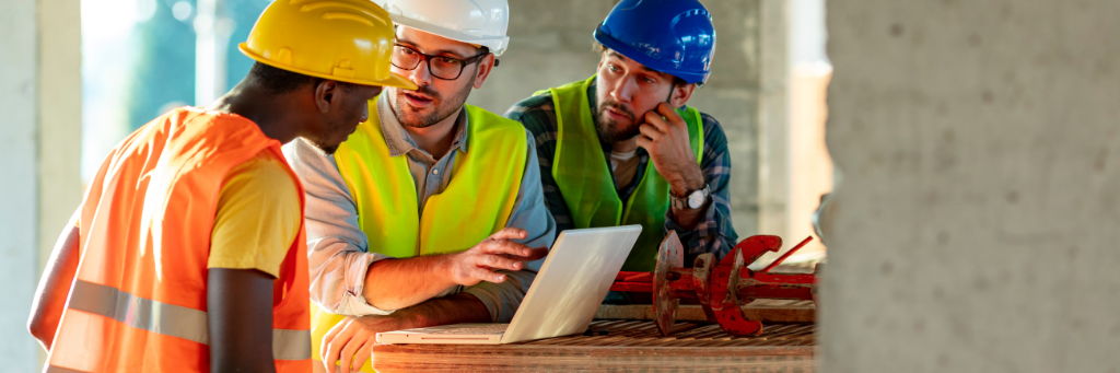 Picture of construction workers wearing hard hats on a construction site discussing building plans