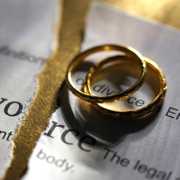 Picture showing two wedding rings on a torn piece of paper with the word Divorce on it.