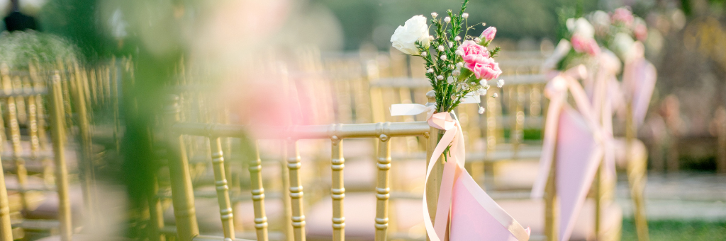 Picture of chairs and pink flowers laid out in preparation for a wedding ceremony